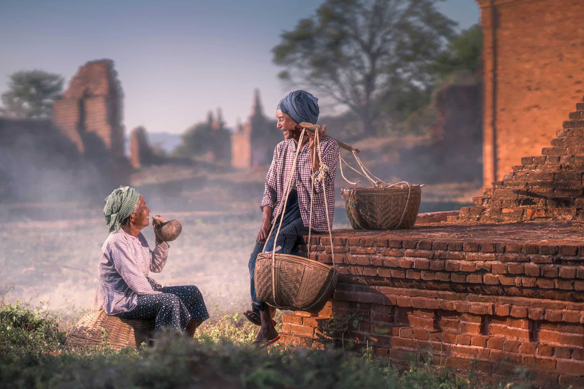 Two women sharing a drink amid the brick temples of Bagan at dawn